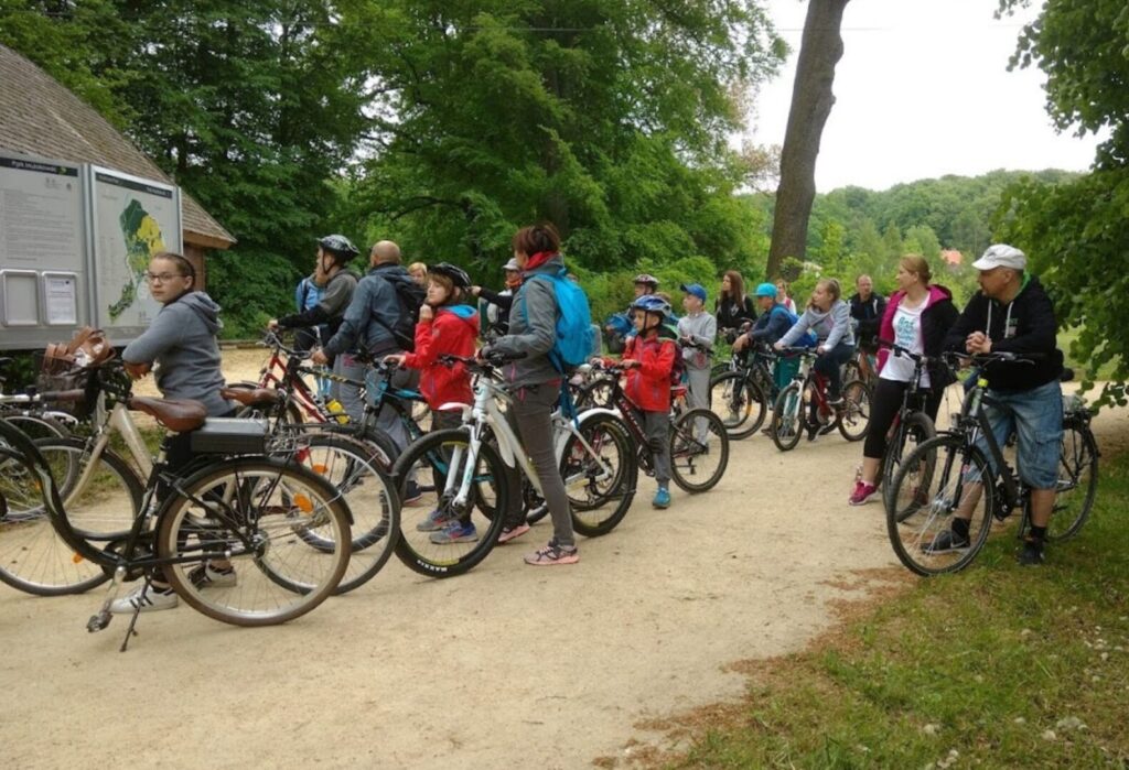 czestnicy integracyjnej wycieczki rowerowej zatrzymani na leśnej drodze, otoczeni zielenią.