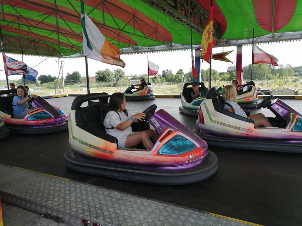 Dzieci jeżdżące kolorowymi samochodzikami na autodromie podczas kolonii letnich.