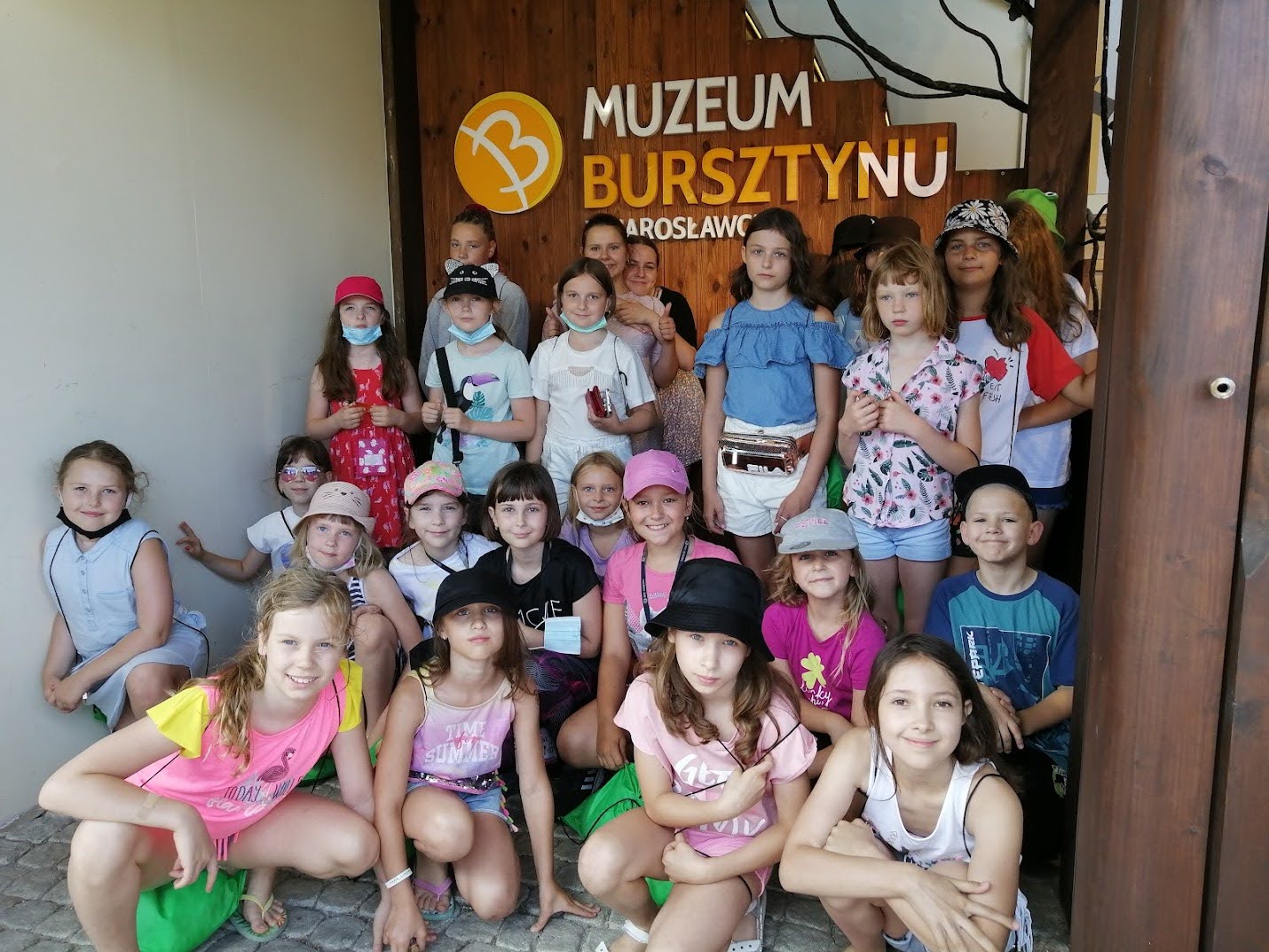 Grupa dzieci pozuje przed wejściem do Muzeum Bursztynu w Jarosławcu podczas wakacyjnej kolonii.