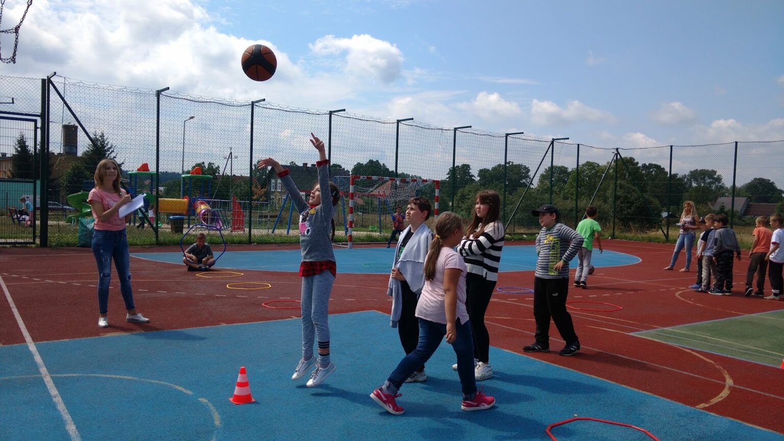 dzieci biorące udział w zajęciach sportowych na boisku podczas letnich półkolonii