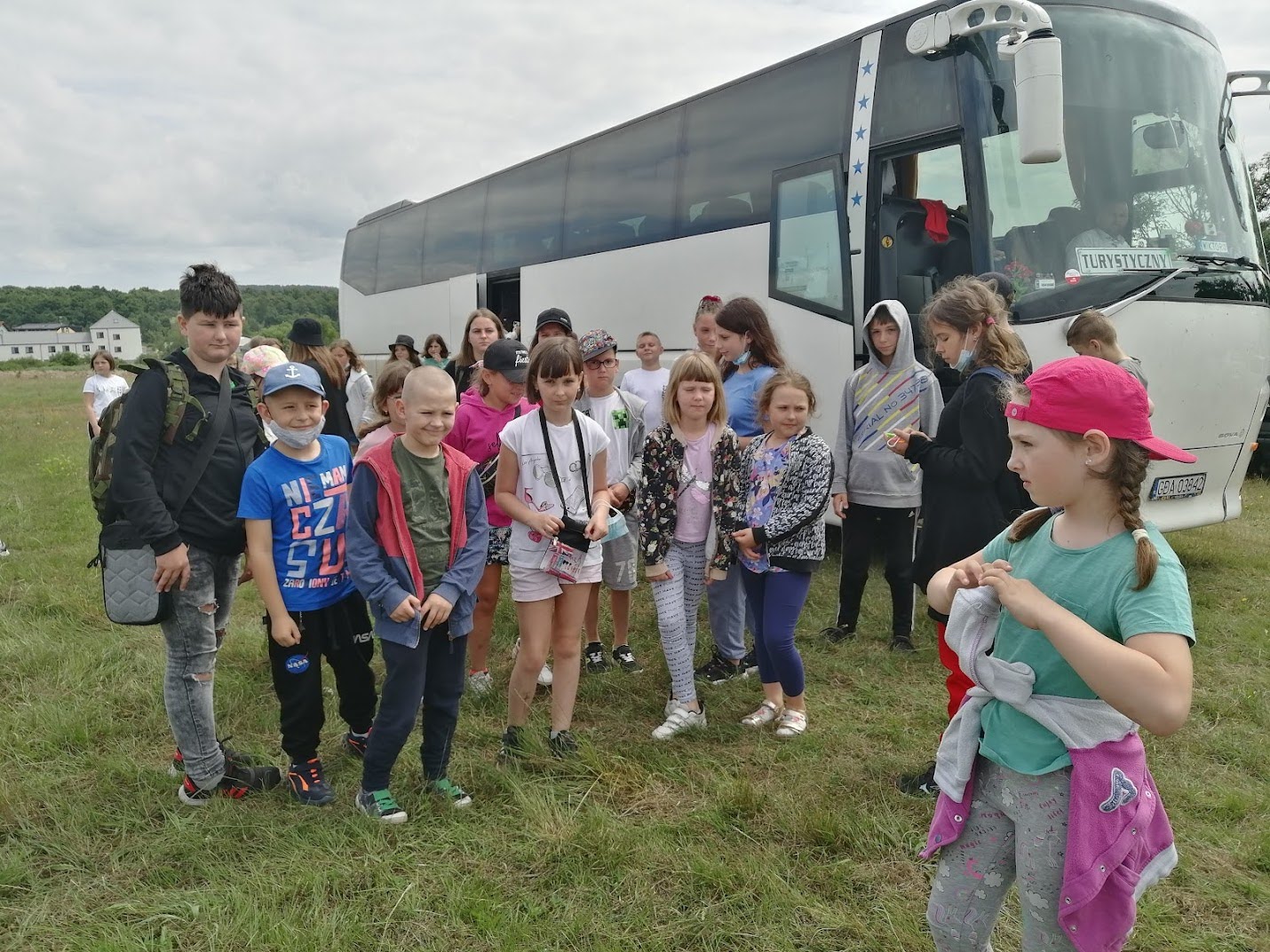 Grupa dzieci i młodzieży stojąca na tle autokaru turystycznego w Jarosławcu podczas kolonii letniej.