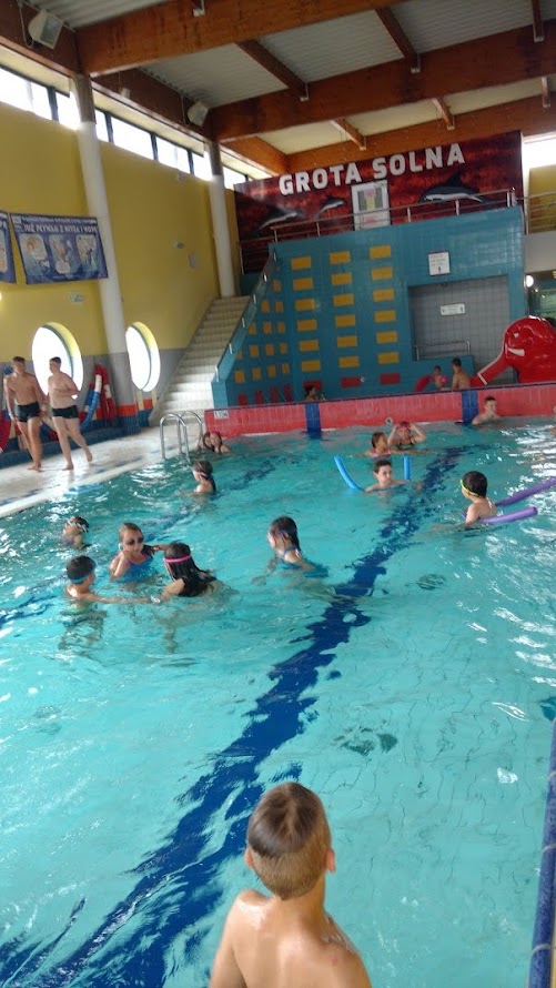 Dzieci uczące się pływać w basenie pod okiem instruktorów podczas zajęć z programu „Umiem Pływać”.